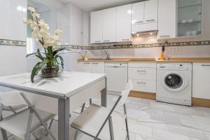 cocina blanca con mesa y lavadora en Apartamento El parador del boticario, en Cádiz