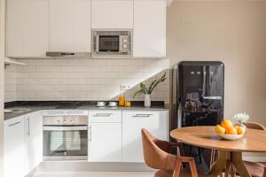 a kitchen with white appliances and a table with a bowl of fruit at Home Art Apartments Salamanca in Madrid
