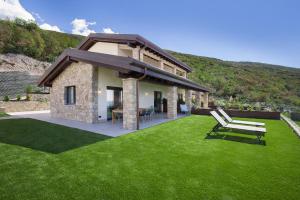 una casa con un cortile verde con una panchina di Villa Divina22- APT Icona con piscina e vista lago a Castelletto di Brenzone Altre 15 foto