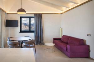 un soggiorno con un divano viola e un tavolo di Villa Divina22- APT Icona con piscina e vista lago a Castelletto di Brenzone