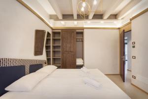 una camera da letto con un letto con lenzuola bianche e un lampadario a braccio di Villa Divina22- APT Icona con piscina e vista lago a Castelletto di Brenzone