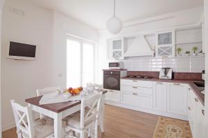 cocina con armarios blancos, mesa y sillas en Casa Armonia by MONHOLIDAY, en Monopoli
