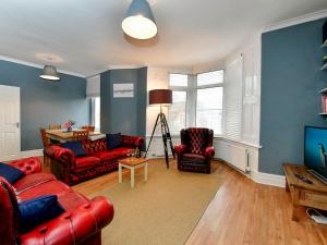 un salon avec des canapés rouges et une télévision dans l'établissement Pass the Keys Spacious 3 Bedroom Apartment Close to City Centre, à Cardiff