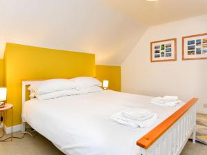- une chambre avec un grand lit blanc et une tête de lit jaune dans l'établissement Pass the Keys Spacious 3 Bedroom Apartment Close to City Centre, à Cardiff