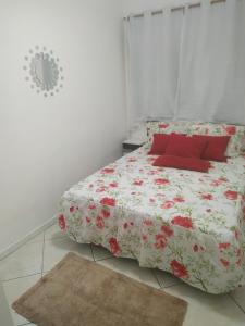 a white bedroom with a bed with red pillows at Confortável apartamento no centro ano bom in Barra Mansa