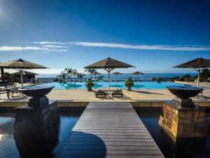 a resort with a pool with umbrellas and a dock at Sankara Hotel & Spa Yakushima in Yakushima