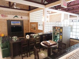 a restaurant with a bar and a table with chairs and a game console at Silvestre Praia Hotel in Imbituba