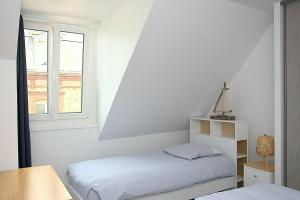 a white room with two beds and a window at Les pieds dans l eau ! in Fécamp