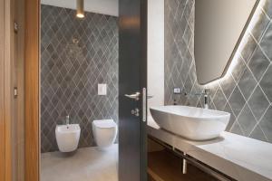 a bathroom with a white sink and a toilet at Villa Divina22 - APT Prima con piscina e vista lago in Castelletto di Brenzone +15 photos