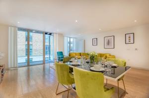 een eetkamer met een tafel en gele stoelen bij Austin David Apartments Royal Wharf in Londen