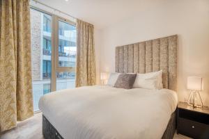 een slaapkamer met een groot bed en een groot raam bij Austin David Apartments Royal Wharf in Londen
