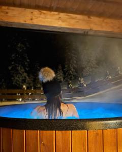 a woman sitting in a hot tub with a tv at Dom na Zielonym Wzgórzu z własną Sauną i Jacuzzi in Łapsze Niżne