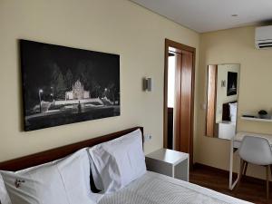 a bedroom with a bed with a picture on the wall at Aliança Alojamento Local in Guarda