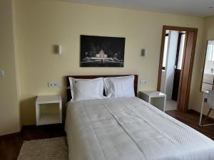 1 dormitorio con 1 cama grande con almohadas blancas en Aliança Alojamento Local, en Guarda