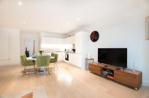 een woonkamer met een televisie en een tafel met stoelen bij Austin David Apartments Royal Wharf in Londen