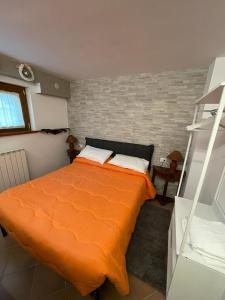 a bedroom with an orange bed and a brick wall at Casa Vacanza Pescocostanzo in Pescocostanzo