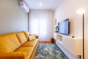 ein Wohnzimmer mit einem Sofa und einem TV in der Unterkunft D&S - Crocodile House S. Bento Apartments in Porto