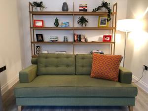 a green couch in a living room with shelves at Chapel View - Huge Apartment near the Beach with Gated Parking in Margate