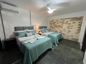 a bedroom with two beds with green linens at Pousada Trilha da Serra in Morretes