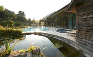 een huis met een vijver voor een gebouw bij Hotel Therme Bad Teinach in Bad Teinach-Zavelstein