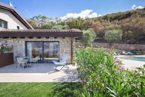 un patio con tavolo e sedie in un cortile di Villa Divina22-APT Unica-Con piscina e vista lago a Castelletto di Brenzone