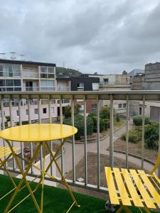 una mesa amarilla y sillas en el balcón en Ma cabane de plage, en Fécamp