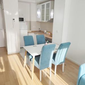 uma cozinha com uma mesa branca e cadeiras azuis em A BLOK1 NEW BELGRADE em Novi Beograd
