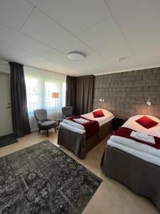 a hotel room with two beds and a chair at Hotell Hammarstrand in Hammarstrand