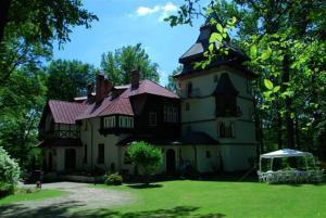 a large house with a gambrel roof on a lawn at Hotel Daria Dworek Myśliwski in Łódź