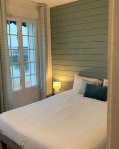 um quarto com uma grande cama branca e uma janela em Le Hublot charmante maison au calme Fécamp vue sur le port em Fécamp