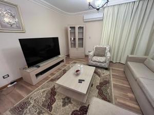 a living room with a television and a couch and a table at Families Only - Rehab - 4th Stage - Ground Floor with Garden in Cairo