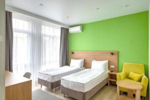 a hotel room with two beds and a green wall at Hotel Rodos in Adler