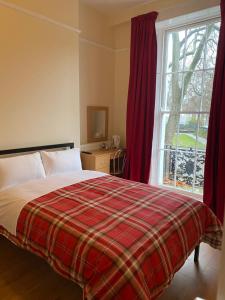 a bedroom with a bed with a plaid blanket and a window at 27 Argyle Square in London