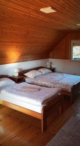 two beds in a room with wooden ceilings at Konak Pahulja TARA in Bajina Bašta