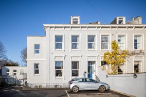 una casa bianca con una macchina parcheggiata di fronte di Curb Properties - Super 2 Bed Apartment 5 Min From Town Centre a Cheltenham