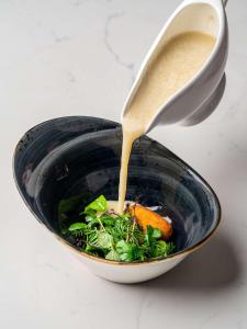 a sauce being poured into a bowl of food at Radisson Collection Hotel, Warsaw in Warsaw