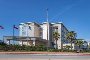 a building with palm trees in front of a street at Clarion Pointe Galveston Seawall in Galveston