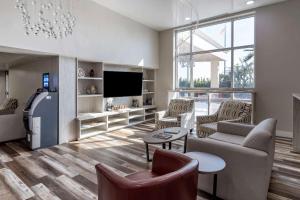 a living room with a couch and chairs and a tv at Clarion Pointe Galveston Seawall in Galveston