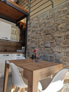 Home holidays- attico arc en ciel في سيستريير: طاولة وكراسي خشبية في مطبخ بجدار حجري