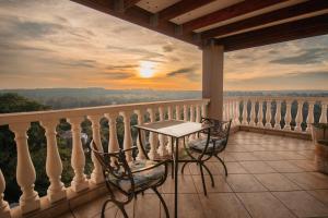 einen Tisch und Stühle auf einem Balkon mit Blick auf den Sonnenuntergang in der Unterkunft All Seasons Boutique Hotel in Pretoria
