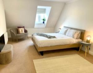 a bedroom with a bed and a chair and a window at Modern Town House near Oxford - 3 double bedrooms in Witney