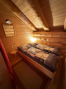a bed in a wooden cabin with a light on it at Almhaus Heidi Nockberge in Patergassen