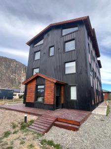 een zwart huis met een houten terras ervoor bij Desierto Suites in El Chalten