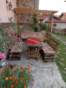 a patio with a table and benches and flowers at Petar Guest House in Bansko