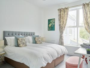 a bedroom with a bed with white sheets and a window at Curb Properties - Super 2 Bed Apartment 5 Min From Town Centre in Cheltenham