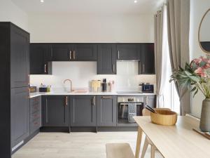 a kitchen with black cabinets and a table at Curb Properties - Super 2 Bed Apartment 5 Min From Town Centre in Cheltenham