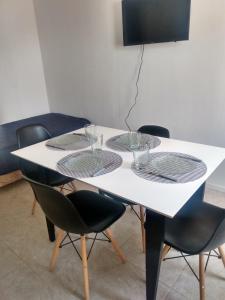 Una mesa blanca con cuatro sillas y vasos. en Complejo JuanXXIII en Godoy Cruz