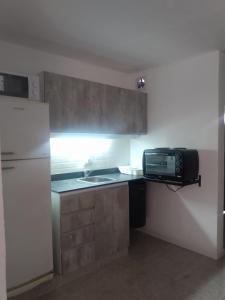 una pequeña cocina con fregadero y microondas en Complejo JuanXXIII en Godoy Cruz