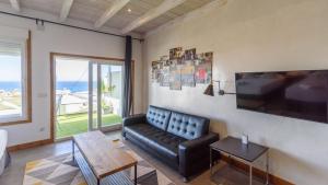 a living room with a black leather couch and a tv at Torre Vigía Torrox by Ruralidays in Torrox