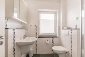 ein weißes Bad mit einem Waschbecken und einem WC in der Unterkunft Oberdeck Haus Oberdeck, Whg 1 in Büsum